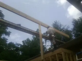Carpenter setting a ridge beam over a new addition frame — Ice Dam Removal by Roofing Brothers in Willoughby