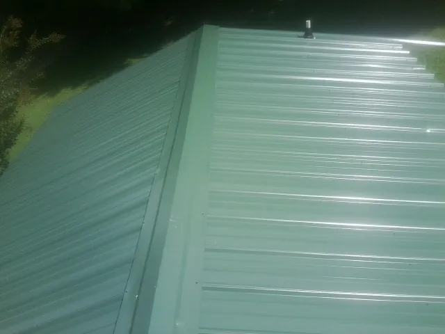 New green metal panels meeting at the ridge of a roof — Flat Roof Repair work by our crew in Willoughby