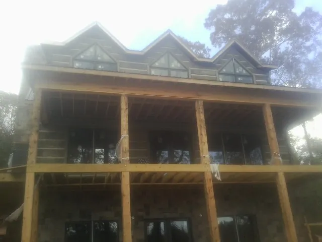 Dormers and porch framing on a large log home under construction — Roof Coating work by our crew in Willoughby