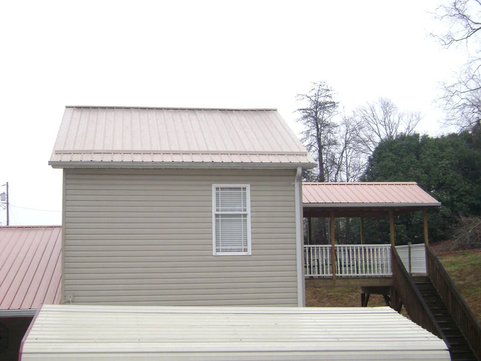 Tan metal roofs on a two story addition and attached porch, from a Roof Replacement job in Willoughby