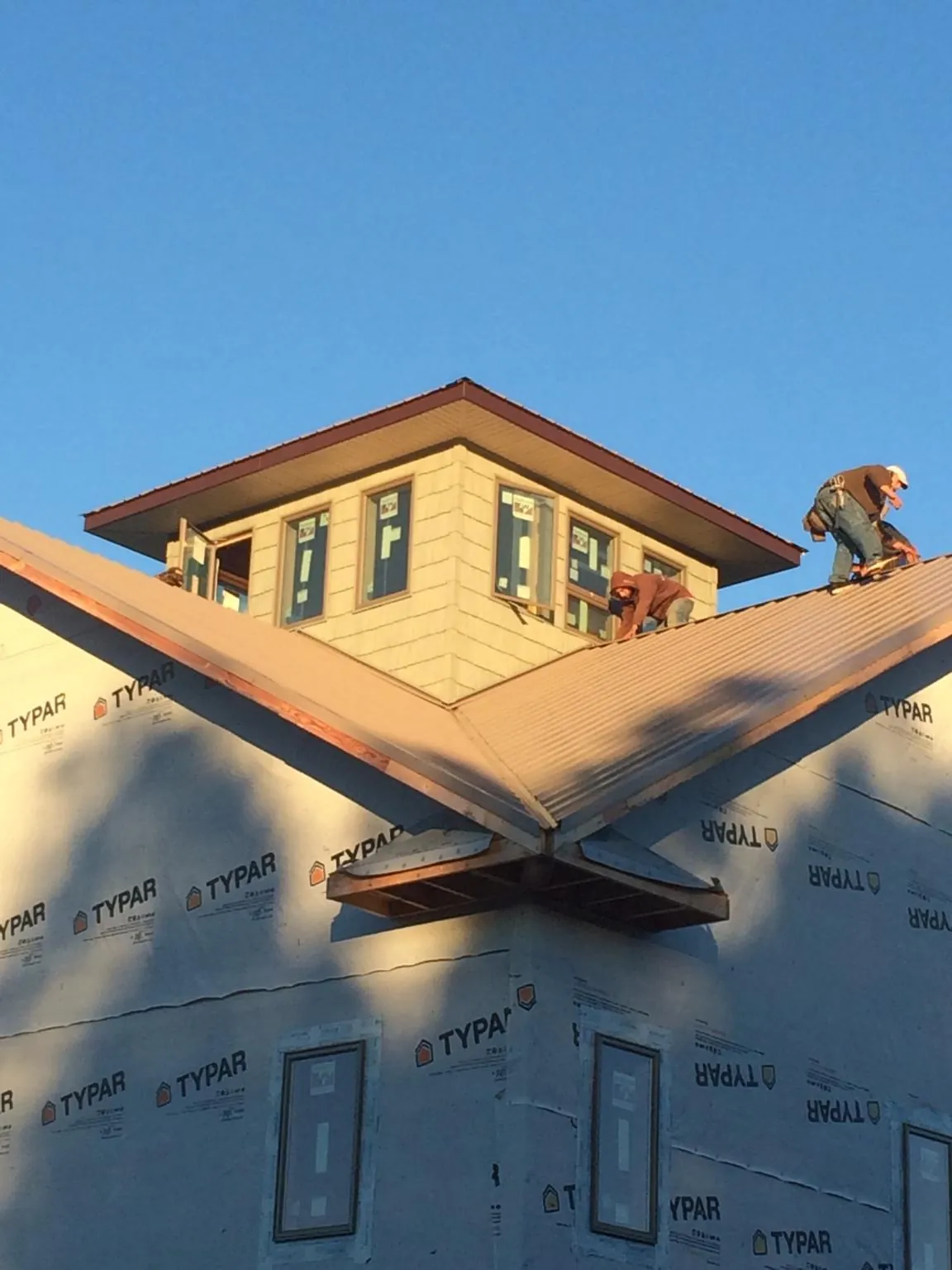 Roofers working around a rooftop cupola on a new metal roof at sunset — Roof Waterproofing in Willoughby by Roofing Brothers